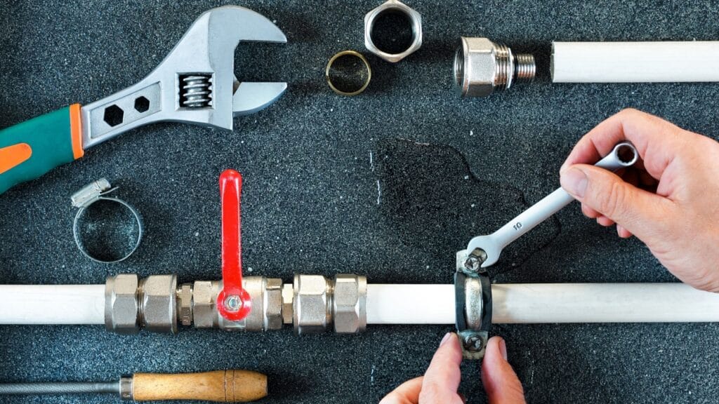 Plumber repairing a pipe valve with an adjustable wrench in Ocoee