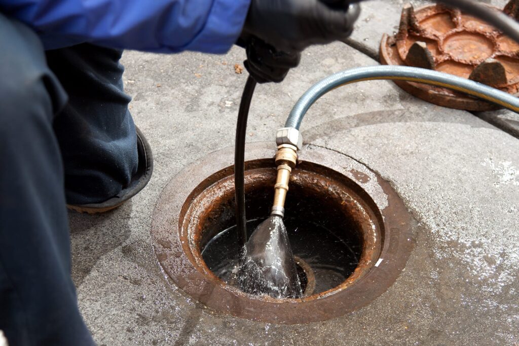 Plumber hydro jetting a sewer line through a manhole in Ocoee