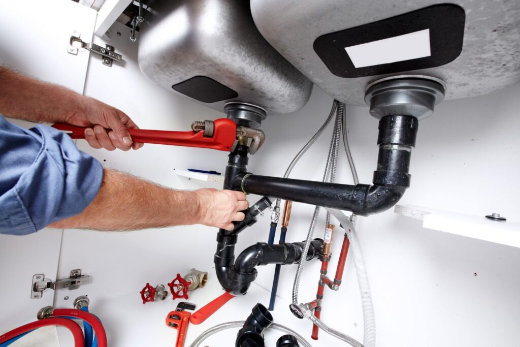 Plumber repairing drain pipes beneath a kitchen sink in Ocoee