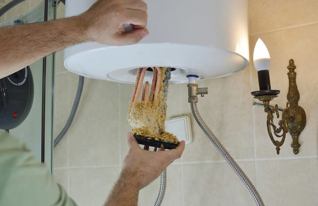 Technician removing mineral buildup from a water heater in Ocoee