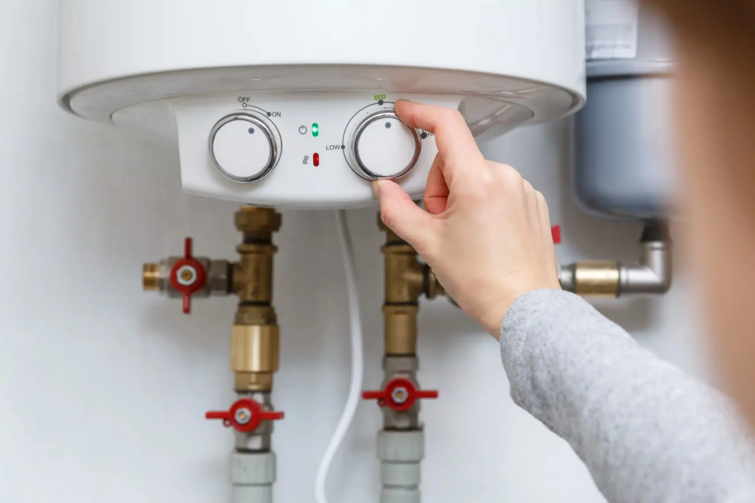 Homeowner adjusting the temperature controls on a water heater in Ocoee
